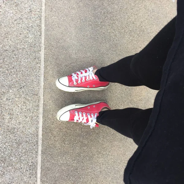 Láb felülről koncepció, tizenéves, aki állandó a talaj háttér piros cipők — Stock Fotó