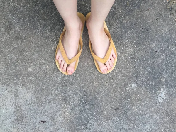Sandalias amarillas en los pies femeninos en el fondo del suelo —  Fotos de Stock