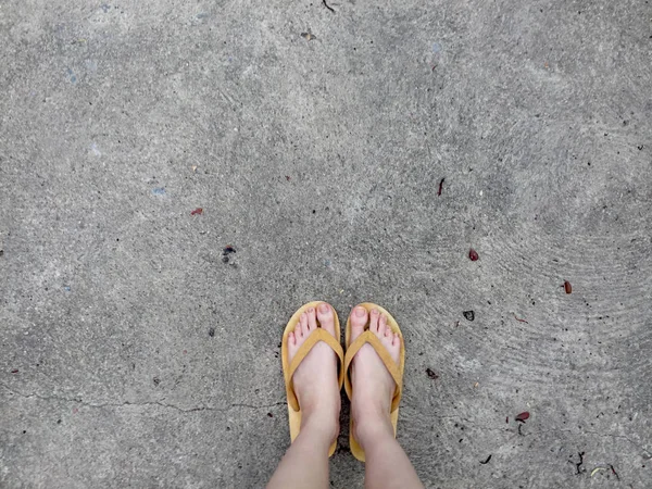 Sandalias amarillas en los pies femeninos en el fondo del suelo —  Fotos de Stock