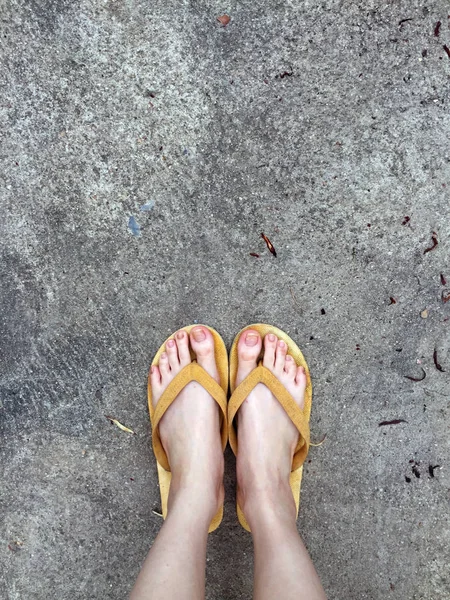 Sandálias amarelas nos pés femininos no fundo do solo — Fotografia de Stock