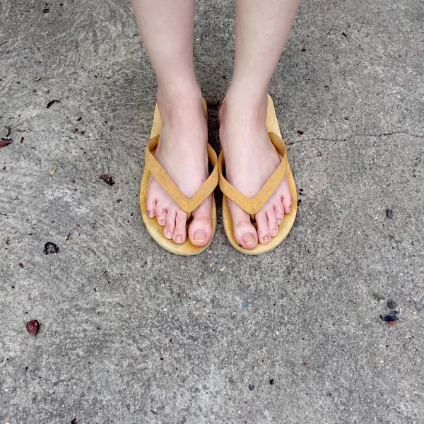 Sandalias amarillas en los pies femeninos en el fondo del suelo — Foto de Stock