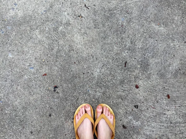 Sandalias amarillas en los pies femeninos en el fondo del suelo — Foto de Stock