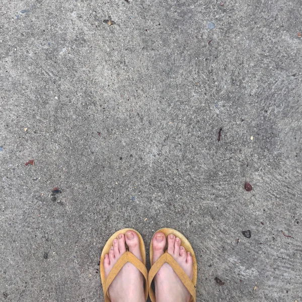 Żółty sandały na nogi kobiece na tle ziemi — Zdjęcie stockowe