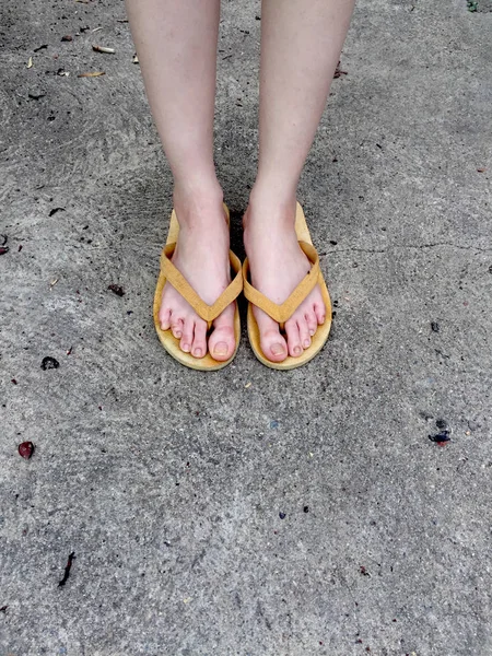 A női lábak, a földön háttér sárga szandál — Stock Fotó