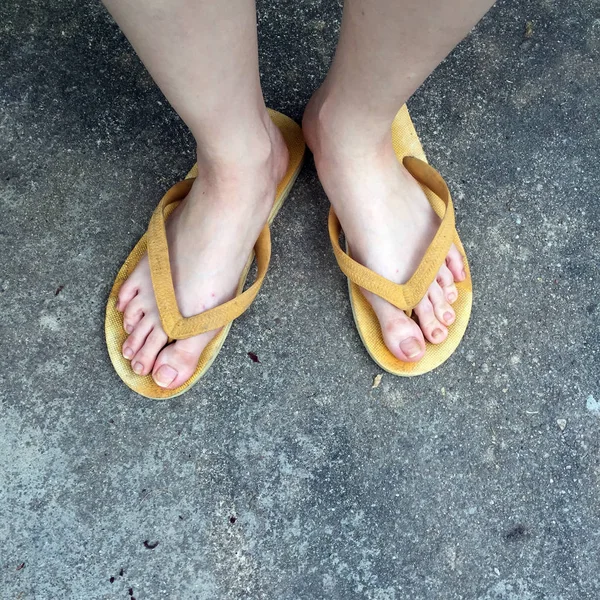 지상 배경에 여성 발에 노란 샌들 — 스톡 사진