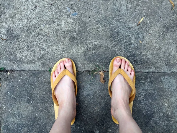 Yellow Sandals on Female Feet on Ground Background