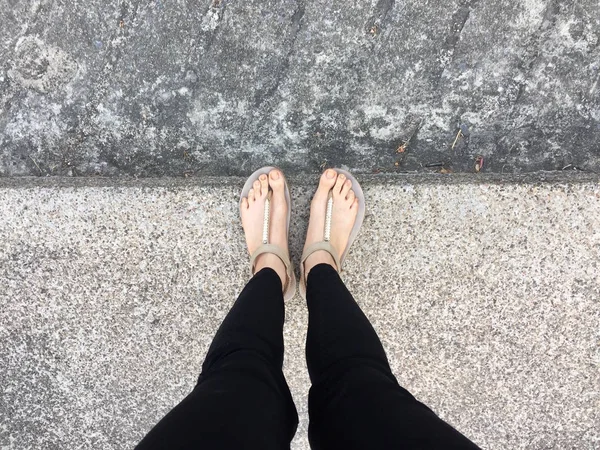 Gouden sandalen op vrouwelijke voeten op de grond achtergrond — Stockfoto