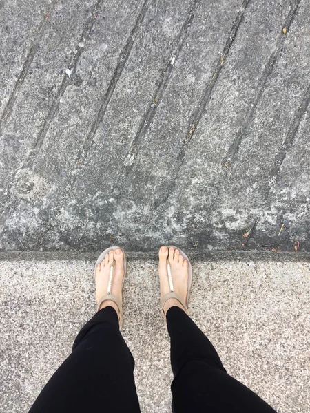 Gouden sandalen op vrouwelijke voeten op de grond achtergrond — Stockfoto