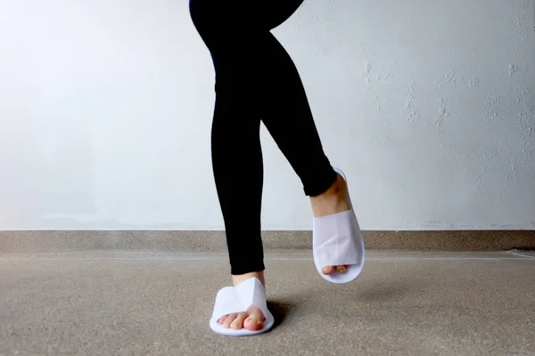 Foto di primo piano della donna che indossa pantofole bianche e pantaloni neri — Foto Stock