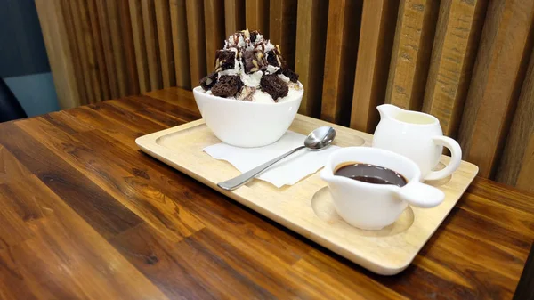 雪フレーク氷菓子と木製のテーブルにアイス Bingsu デザート ボウル チョコレートと甘いソースをトッピング — ストック写真