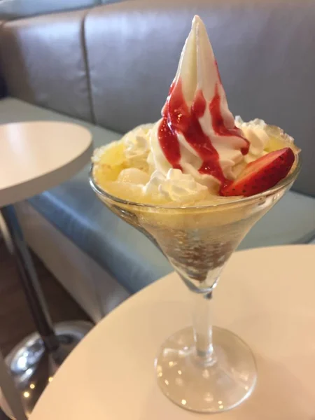 Crema batida de helado suave con salsa de fresa en la mesa —  Fotos de Stock