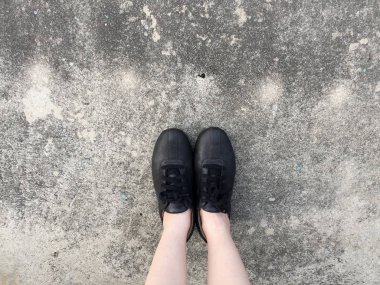 Beton zemin üzerinde duran siyah ayakkabı