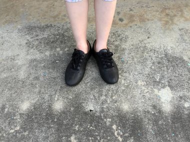 Beton zemin üzerinde duran siyah ayakkabı