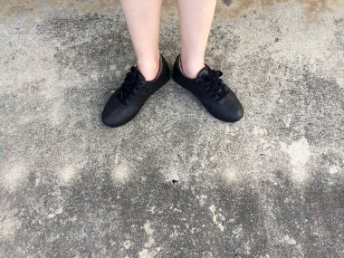 Beton zemin üzerinde duran siyah ayakkabı