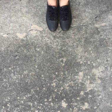 Beton zemin üzerinde duran siyah ayakkabı