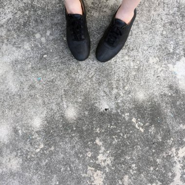 Beton zemin üzerinde duran siyah ayakkabı