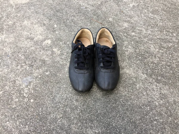 Παλιά μαύρα παπούτσια στο τσιμεντένιο πάτωμα φόντο — Φωτογραφία Αρχείου
