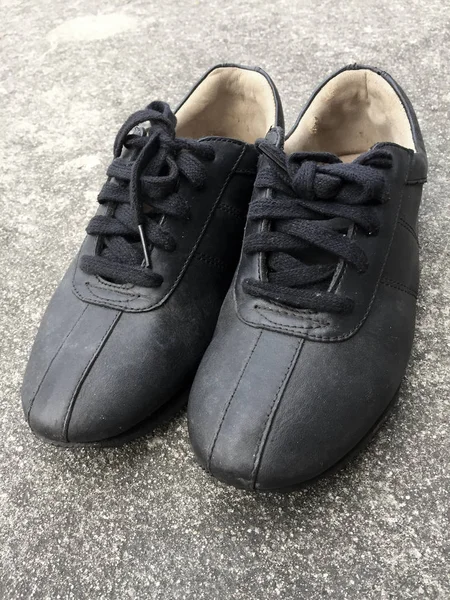 Stare czarne buty na tle posadzek betonowych — Zdjęcie stockowe