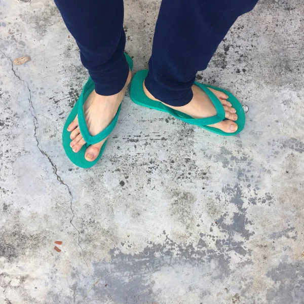 Pies de una mujer con sandalias verdes en el piso de hormigón viejo —  Fotos de Stock