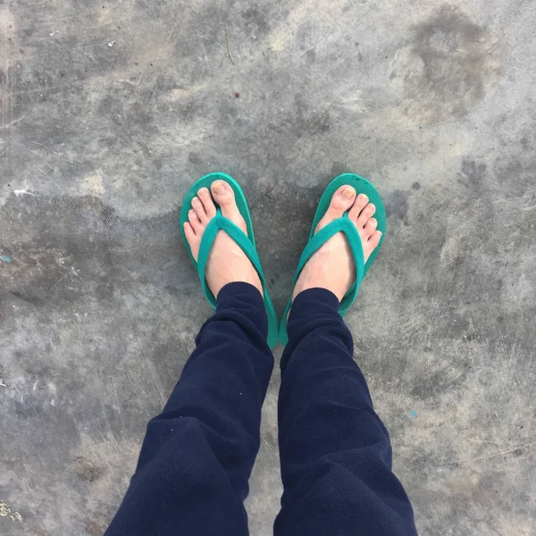 Piedi di una donna che indossa sandali verdi sul vecchio pavimento di cemento — Foto Stock