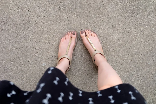 Selfie pieds portant des sandales en or et robe sur fond de sol — Photo