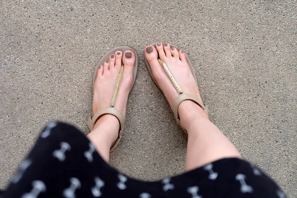 Selfie voeten dragen gouden sandalen en jurk op grond achtergrond — Stockfoto