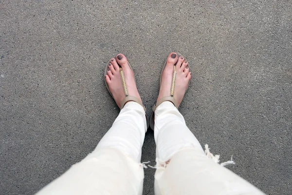 Pies selfie con sandalias de oro y pantalones vaqueros blancos en el suelo —  Fotos de Stock