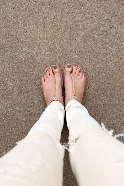 Selfie Feet portant des sandales en or et des jeans blancs au sol — Photo