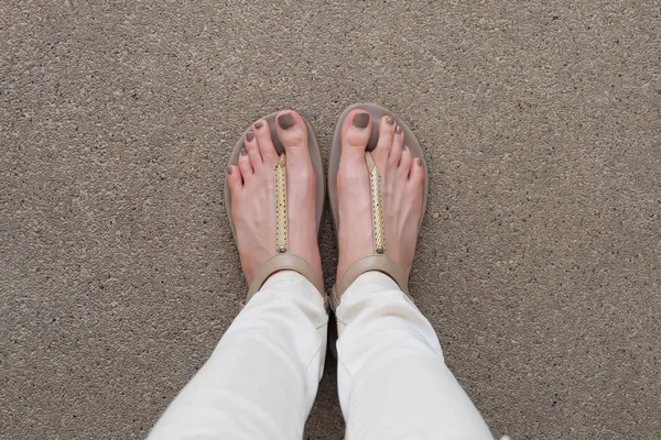 Selfie voeten dragen gouden sandalen en witte Jeans op grond — Stockfoto