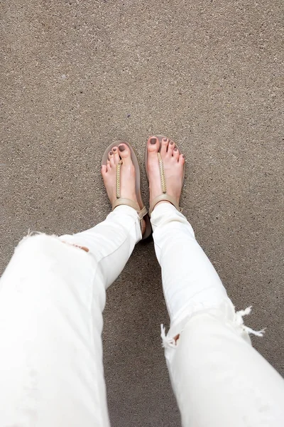 Pies selfie con sandalias de oro y pantalones vaqueros blancos en el fondo del suelo —  Fotos de Stock