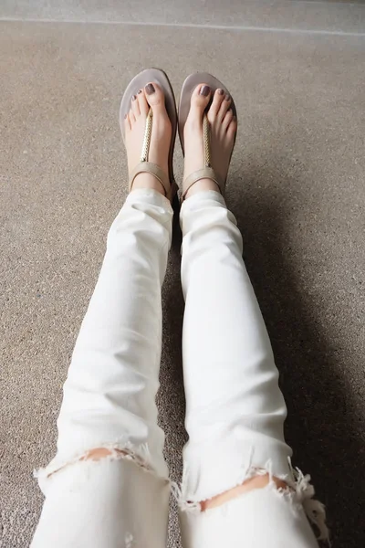 Selfie Feet Wearing Gold Sandals and White Jeans on Ground Background — Stock Photo, Image