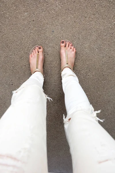 Selfie Füße tragen goldene Sandalen und weiße Jeans auf dem Boden Hintergrund — Stockfoto