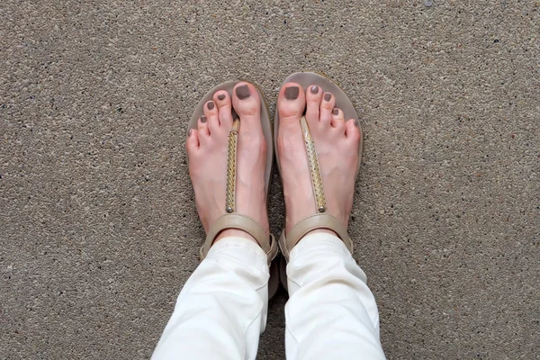 Selfie piedi indossando sandali d'oro e jeans bianchi su sfondo terra — Foto Stock