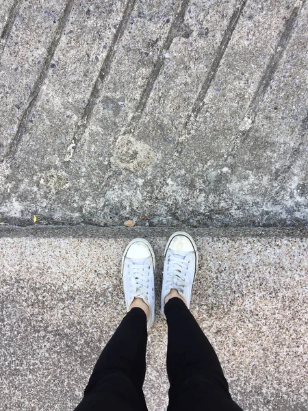 Nahaufnahme von einer Frau, die weiße Turnschuhe auf der Straße trägt — Stockfoto