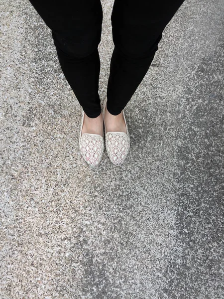 Gros plan des pieds de fille portant des sandales tissées dans le sol — Photo