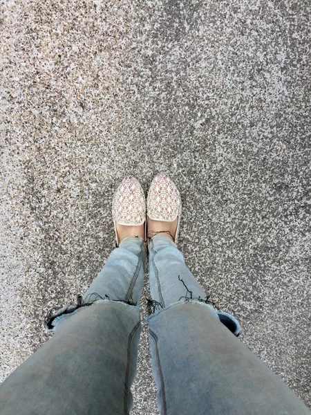 Gros plan des pieds de fille portant des sandales tissées dans le sol — Photo