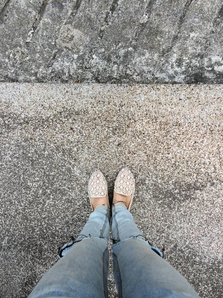 Närbild av flickans fötter bär väva sandaler i marken — Stockfoto