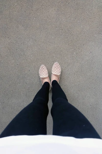 Gros plan des pieds de fille portant des sandales tissées dans le sol — Photo