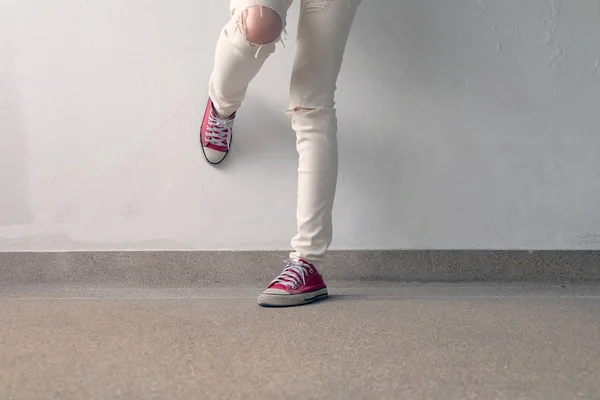 Foto di primo piano della donna che indossa scarpe da ginnastica rosse sullo sfondo del pavimento in cemento — Foto Stock