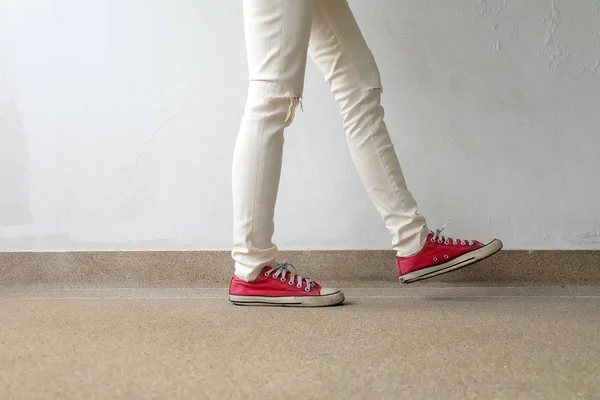 Foto de primer plano de una mujer que usa zapatillas rojas en el fondo de hormigón —  Fotos de Stock