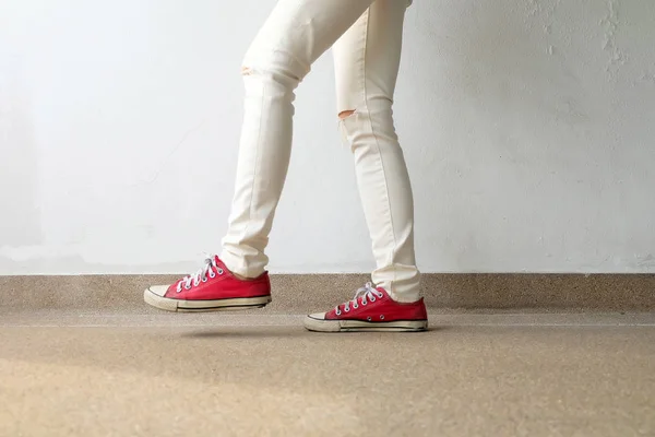 Foto de primer plano de una mujer que usa zapatillas rojas en el fondo de hormigón —  Fotos de Stock