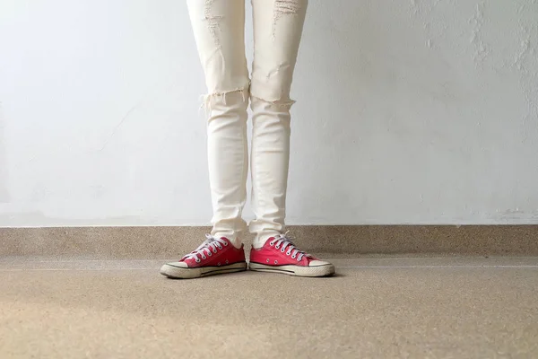 Foto de primer plano de una mujer que usa zapatillas rojas en el fondo de hormigón —  Fotos de Stock