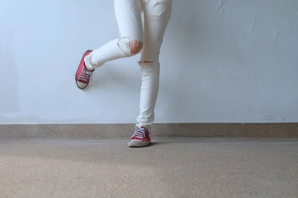 Foto di primo piano della donna che indossa scarpe da ginnastica rosse sullo sfondo del pavimento in cemento — Foto Stock