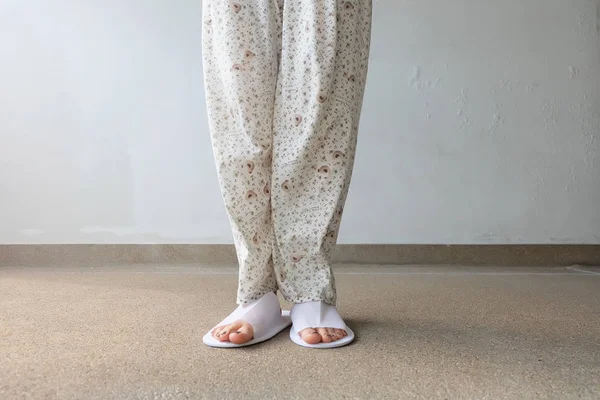 Foto de primer plano de De los pies de la mujer con zapatillas blancas en interiores en el suelo — Foto de Stock