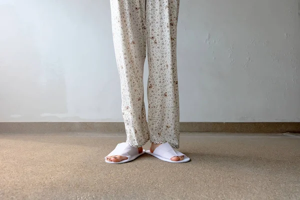Foto de primer plano de De los pies de la mujer con zapatillas blancas en interiores en el suelo — Foto de Stock