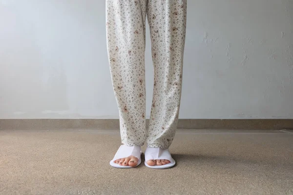 Närbild foto av från kvinna fötter bär vita tofflor inomhus på marken — Stockfoto