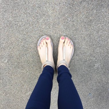 Ayakları ile kahverengi altın sandalet ve mavi pantolon zemin zemin üzerine kadın ayakları üzerinde çivi kadar kapatın