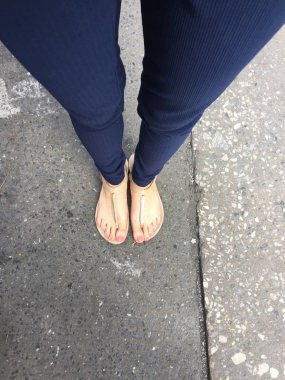 Ayakları ile kahverengi altın sandalet ve mavi pantolon zemin zemin üzerine kadın ayakları üzerinde çivi kadar kapatın