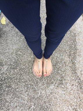 Ayakları ile kahverengi altın sandalet ve mavi pantolon zemin zemin üzerine kadın ayakları üzerinde çivi kadar kapatın