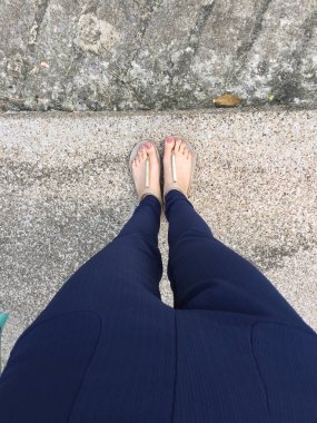 Ayakları ile kahverengi altın sandalet ve mavi pantolon zemin zemin üzerine kadın ayakları üzerinde çivi kadar kapatın